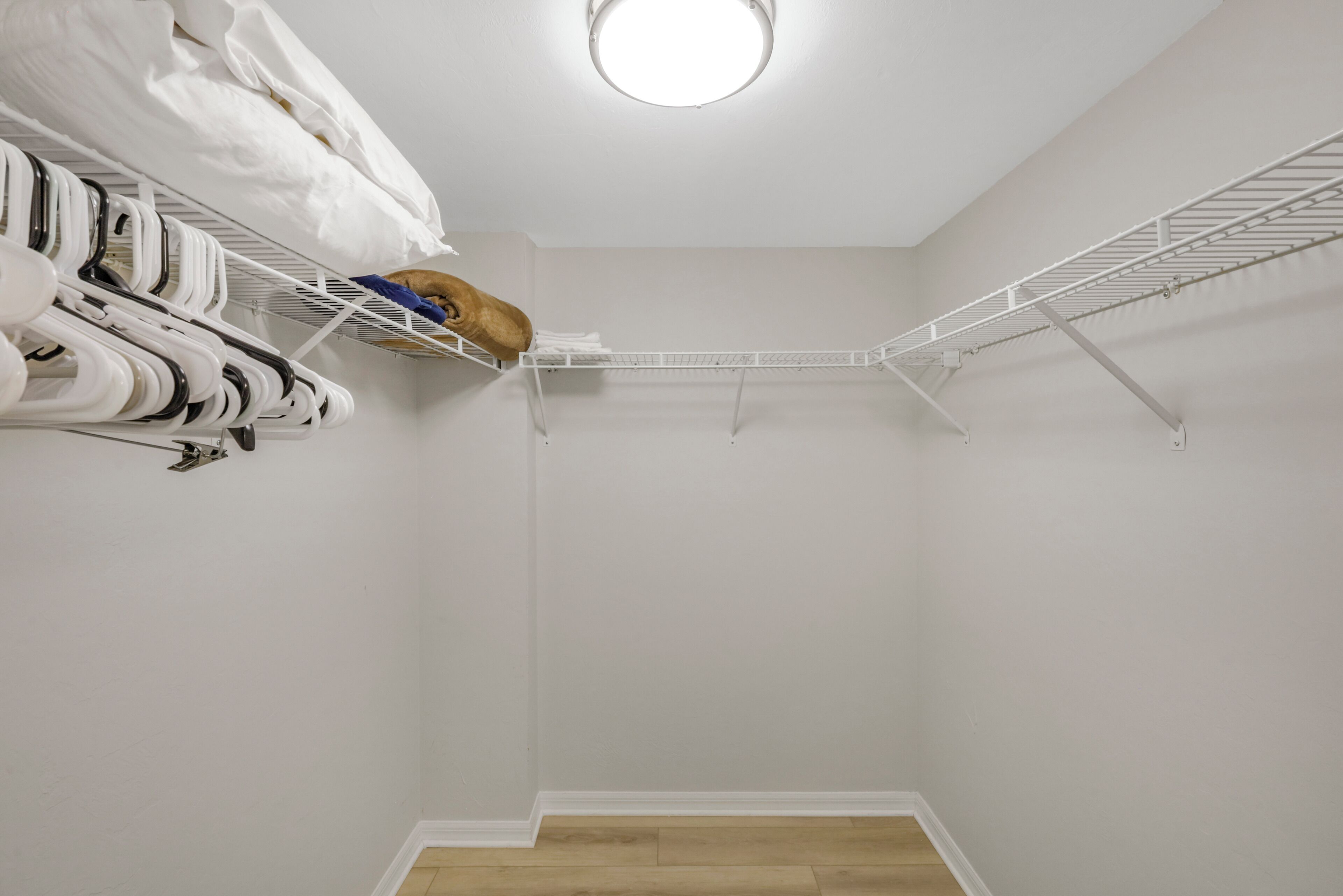 A closet with hanging clothes and a metal shelf unit.