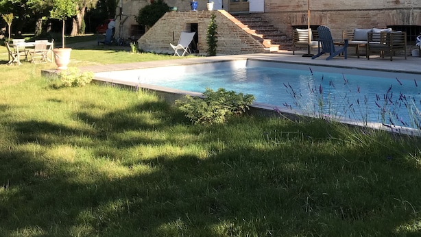 Ein historisches Gebäude mit Schwimmbad, Außenbereich zum Sitzen und einer Treppe zum Eingang.