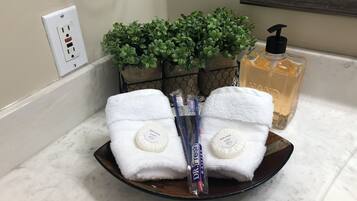 Un meuble de salle de bain avec une serviette blanche, une bouteille de savon de bain de la marque Dr. Fresh et une petite plante en pot.