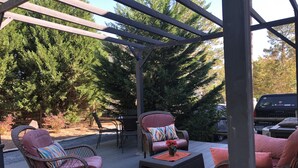 A covered outdoor patio with wicker furniture and a table, surrounded by trees. - Located in # 6 golf community, close to First Health Moore Regional Hospital.  (Pinehurst)