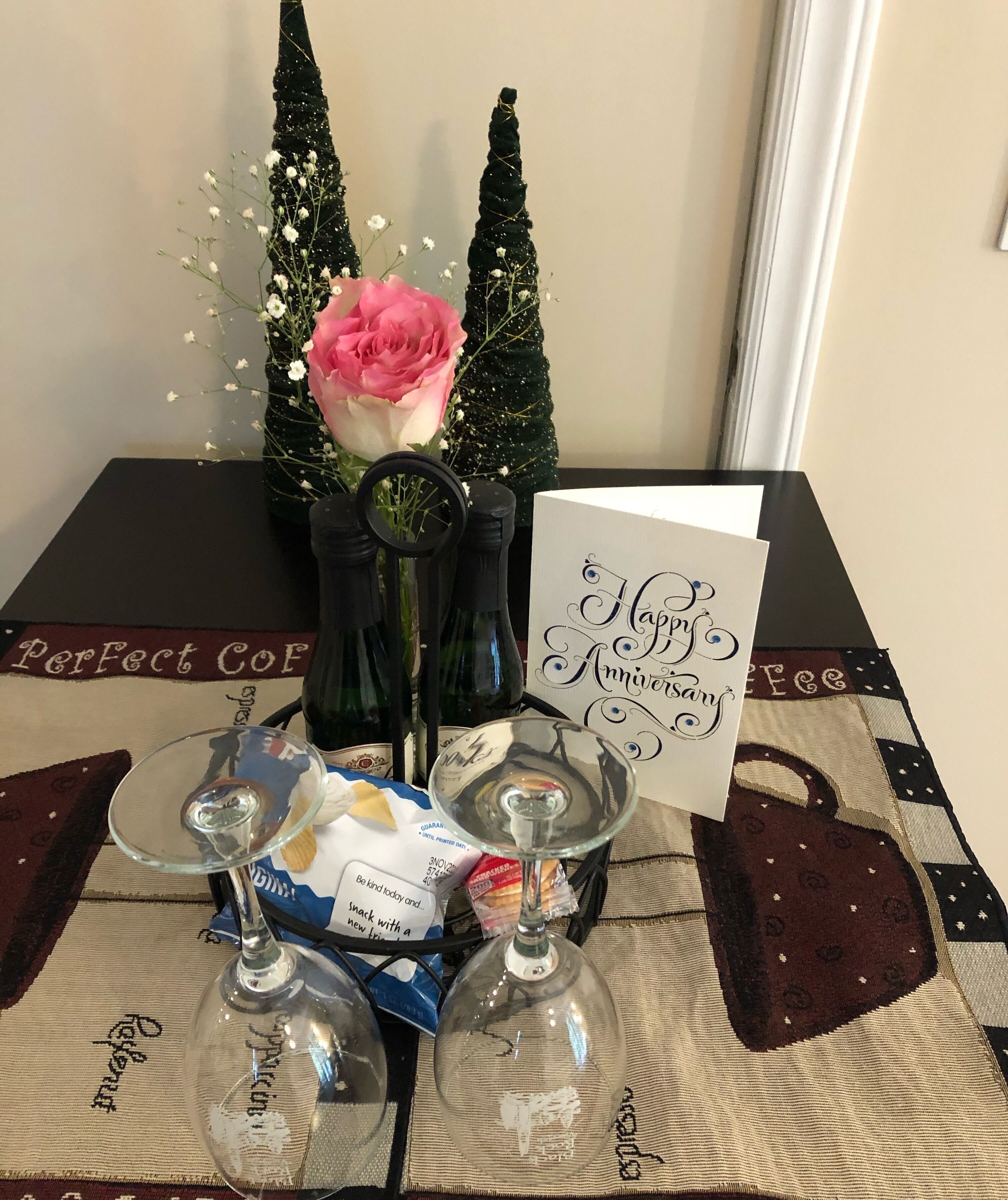 Una taula amb un got de vi, una carta i un ram de flors.