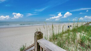 Een strand met een houten vogelkijkhut en grasduinen.