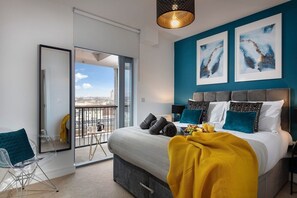 A modern bedroom with a large bed, a balcony with a city view, and abstract art on the wall.
