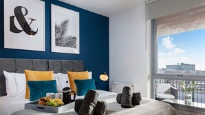 A modern hotel room with a large bed, a view of the city, and artwork on the wall. - Plymouth Sea-View PENTHOUSE-Habita Property (England)
