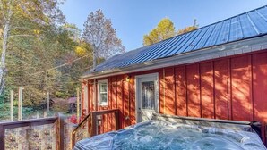 A hot tub on a wooden deck with a red building in the background.