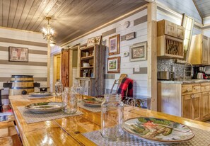 Una cocina rústica con armarios de madera, una mesa de comedor de madera dispuesta con platos y una araña.