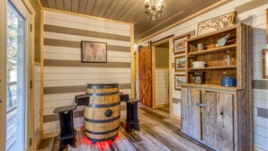 A rustic interior with wooden walls, a wooden barrel, and a cabinet with shelves.