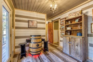 Un interior rústico con paredes de madera, un barril de madera y un mueble con estantes.