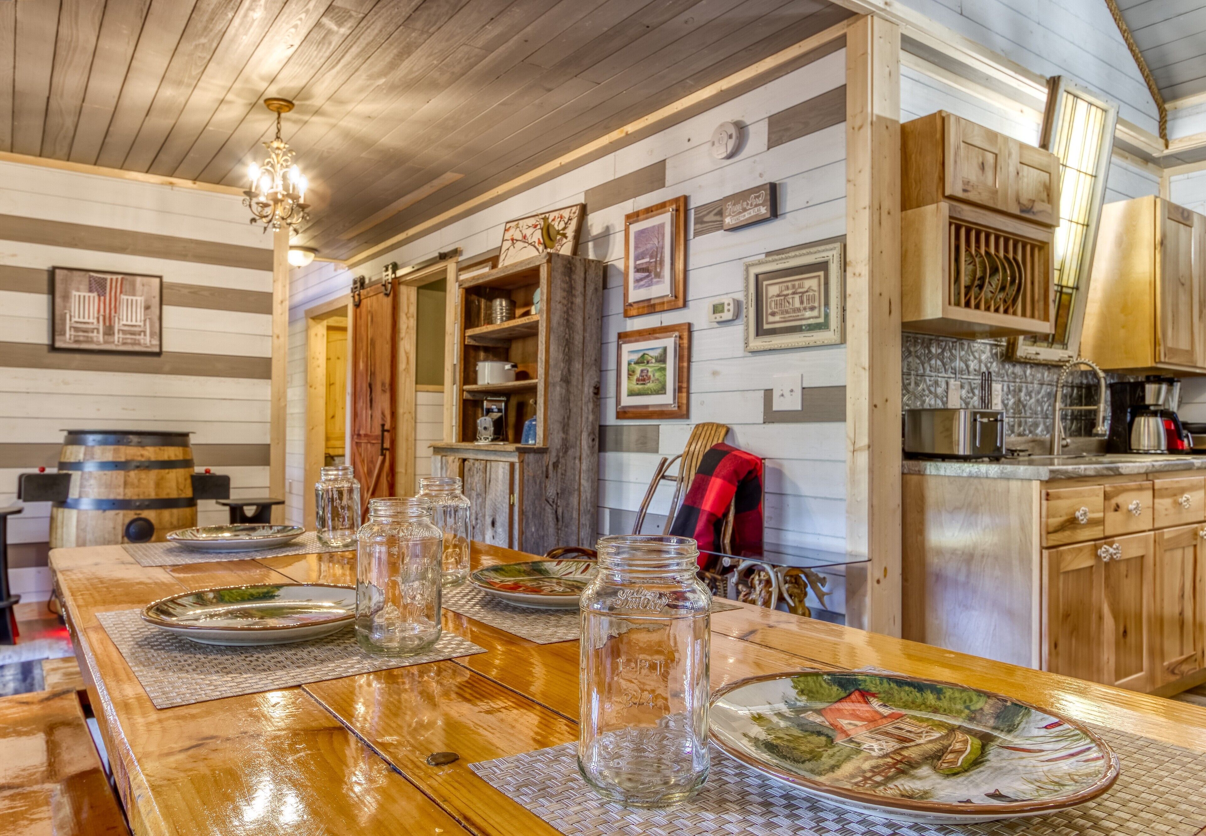 Una cocina rústica con armarios de madera, una mesa de comedor de madera dispuesta con platos y una araña.
