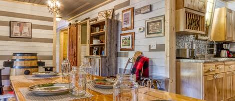 Una cocina rústica con armarios de madera, una mesa de comedor de madera dispuesta con platos y una araña.