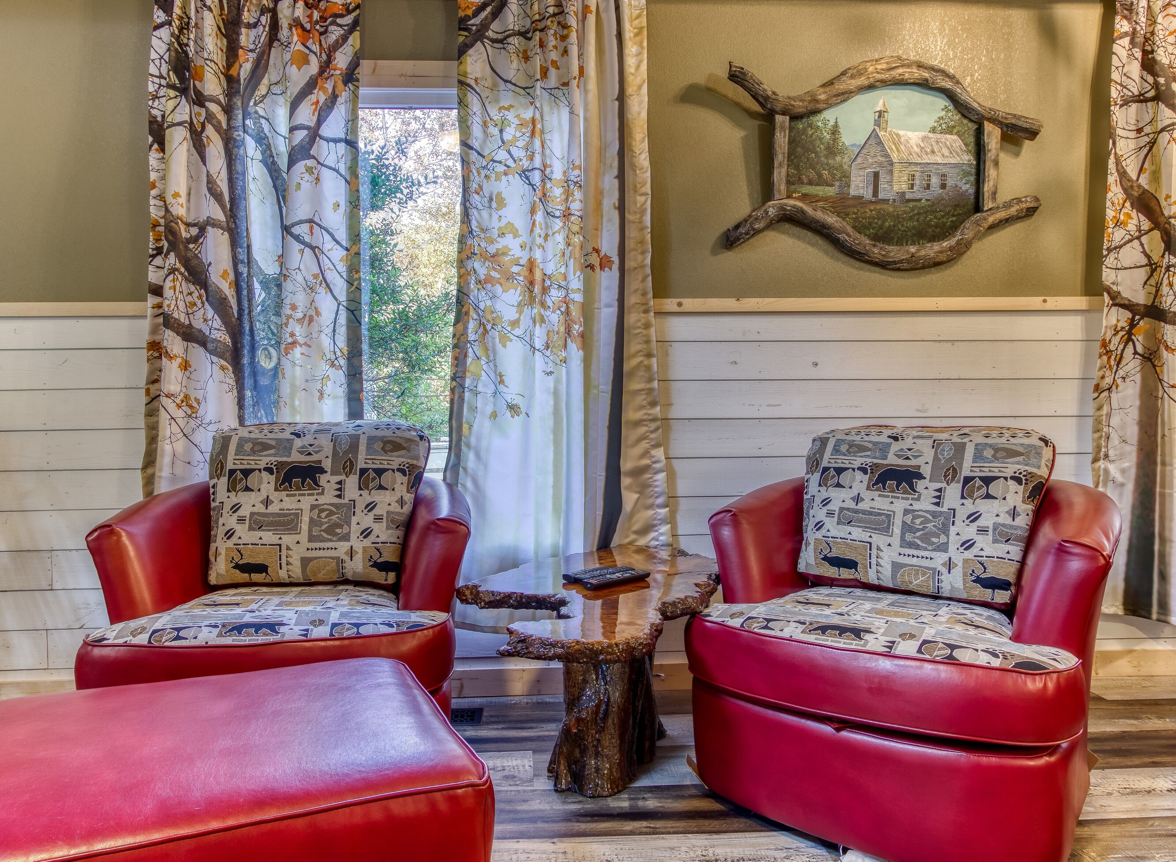 Une pièce chaleureuse avec deux fauteuils en cuir rouge ornés de coussins à motifs, une petite table en bois et une décoration murale rustique.