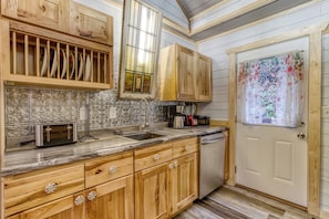 A kitchen with wooden cabinets, a microwave, a coffee maker, and a dishwasher. - Fire-Pit | Hot Tub | WiFi | Pet Friendly | Arcade | Close to Attractions (Sevierville)
