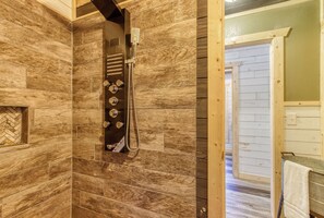 A bathroom with wooden walls and a shower area.