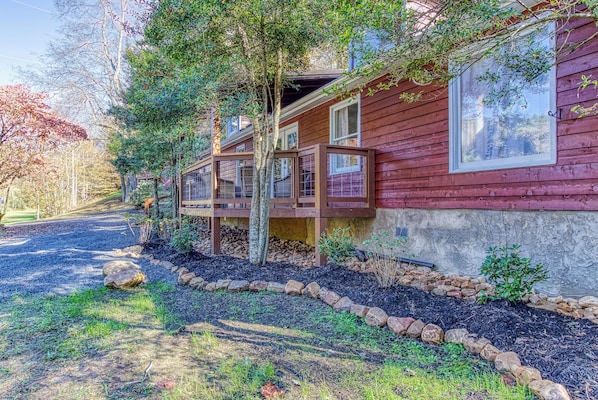 A wooden cabin with a porch, surrounded by a landscaped garden with rocks and mulch. - Fire-Pit | Hot Tub | WiFi | Pet Friendly | Arcade | Close to Attractions (Sevierville)