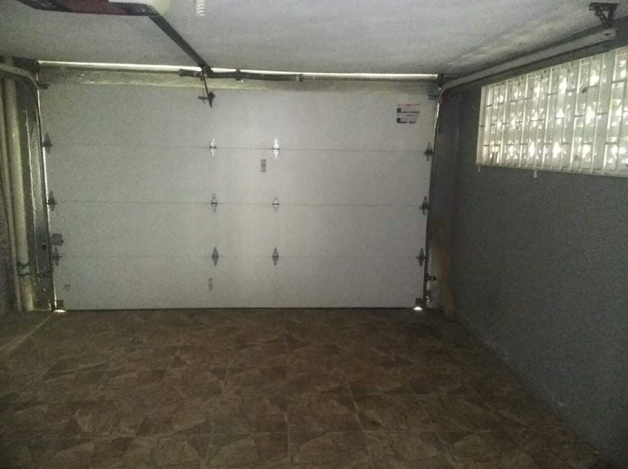 Un garage avec une porte fermée, un sol carrelé et une fenêtre sur le côté droit.
