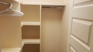 A walk-in closet with open shelves and a hanging rod. - Stylish Heritage Apt Ideal For Long Stays - 3 BR with Jacuzzi (Fort McMurray)