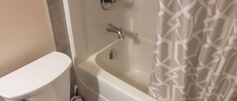 Un baño con inodoro, bañera y cortina de ducha.