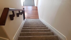 A carpeted staircase with a wooden handrail and a light-colored wall. - Stylish Heritage Apt Ideal For Long Stays - 3 BR with Jacuzzi (Fort McMurray)