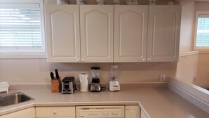 A kitchen with white cabinets, a toaster, a blender, and a dishwasher. - 3 Bedroom Furnished Apartment  suitable for Company Staff with Large Yard  Space (Fort McMurray)