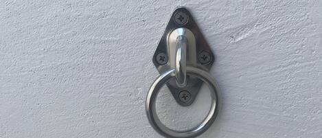A metal door knocker mounted on a white textured wall.