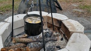 A portable outdoor cooking setup with a pot on a portable stove, surrounded by a stone fire pit. - MANATEE WATCH DEN 1 BEDROOM PET FRIENDLY (Crystal River)