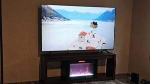 A flat-screen TV on a wooden TV stand with a fireplace below it. - MANATEE WATCH DEN 1 BEDROOM PET FRIENDLY (Crystal River)