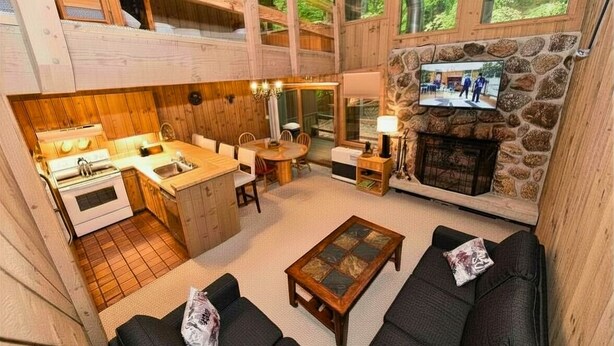 A cabin interior with a kitchen, dining area, fireplace, and seating. - Spacious Kearsarge Woods Unit w Association Pool & Tennis 2 Mins to Downtown (North Conway)