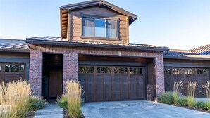 Une maison moderne à deux étages, dotée d’un garage, d’une façade en briques et d’une allée en béton.