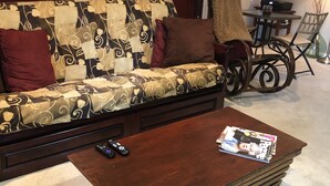 Un salon avec un canapé à motifs, une table basse en bois, une lampe et un tableau encadré au mur.