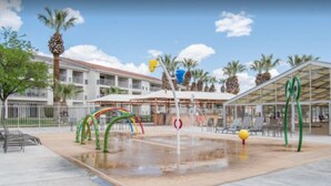 An outdoor swimming pool area with a water slide, palm trees, and a covered seating area. - "Desert Blossom"- Exceptionally Relaxing Vacation Destination! (St. George)
