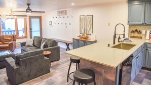 Una cocina moderna con una isla central, taburetes de bar y un comedor con sofá y sillas.