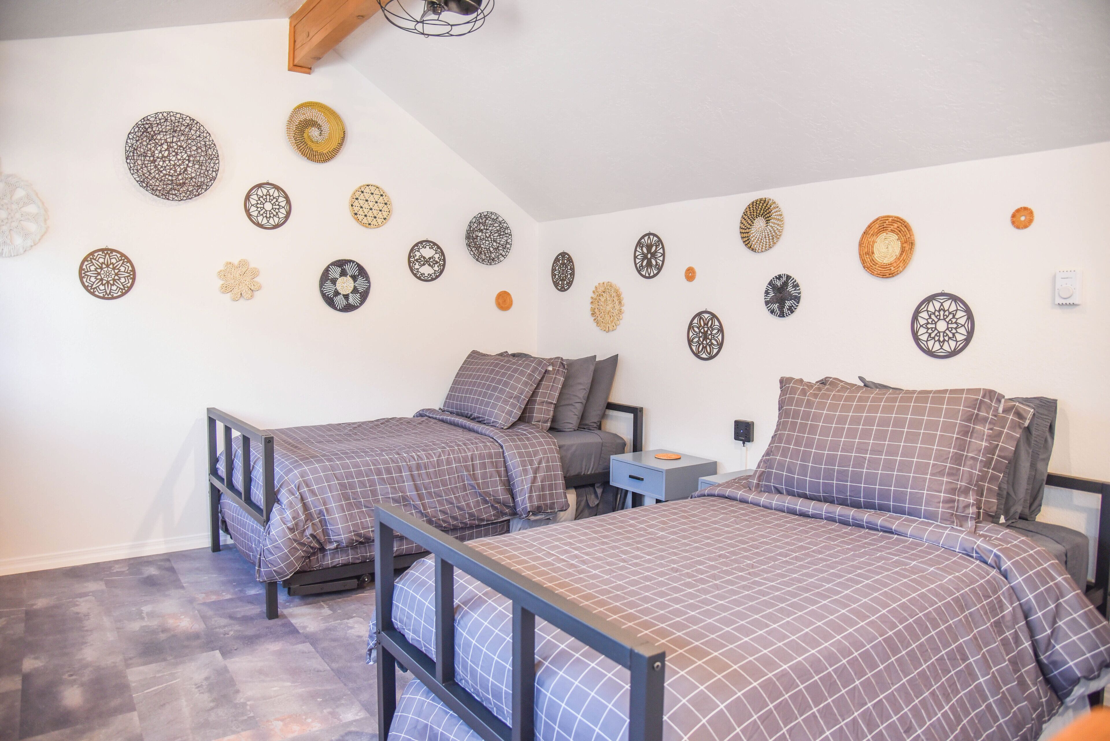 A bedroom with two beds, a nightstand, and decorative wall art.