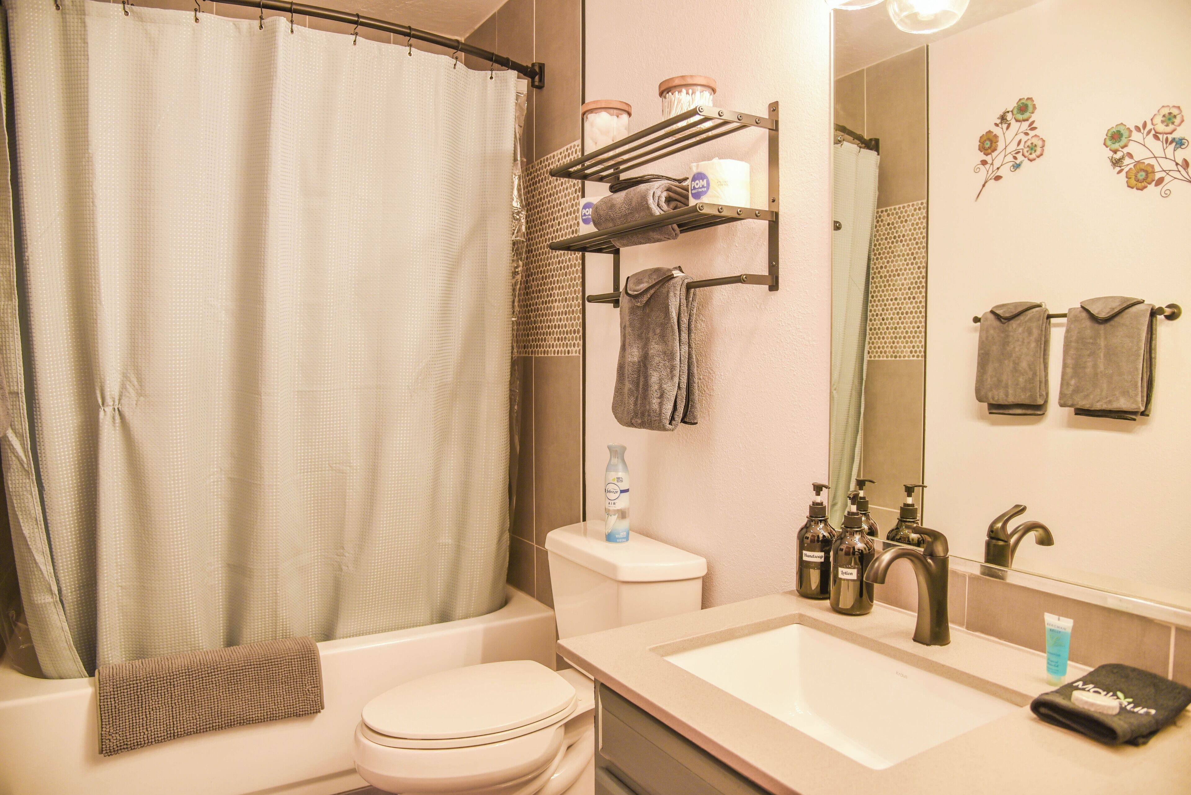 A bathroom with a shower curtain, toilet, sink, and towel rack.