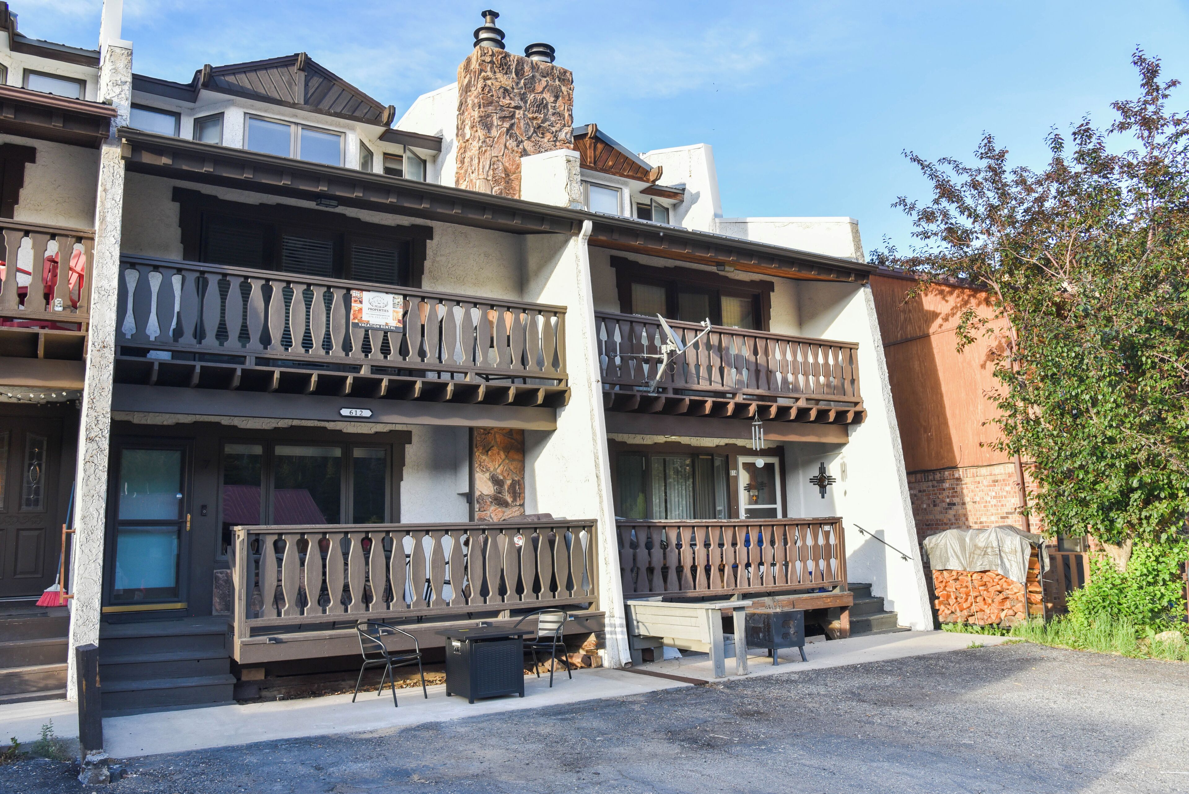 A multi-story building with balconies, a visible address number, and a small outdoor seating area.