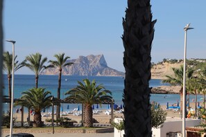Ein Strand mit Palmen, Sonnenschirmen und einem Berg im Hintergrund.