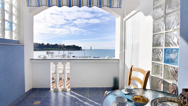 Ein Balkon mit Blick auf das Meer, ein Tisch mit einer Auswahl an Keksen und ein Stuhl.