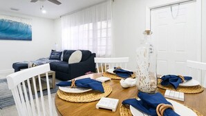 A living room with a dark sofa, white chairs, a wooden coffee table, and a ceiling fan. - Beautiful Waterfront Condo on Canal with Pool & Walk to Beach! Boat Watch! 2b/2b (Pompano Beach)
