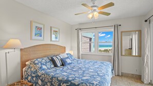 A bedroom with a bed, a ceiling fan, a window with a view, and a nightstand. - 🌿 Select View Condo — Gulf Strand Resort, St. Pete Beach (St Pete Beach)