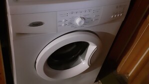 En tvättmaskin med frontmatning i ett badrum med gröna, mönstrade kakelplattor.