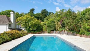 Une piscine rectangulaire à l’eau d’un bleu limpide, entourée d’une terrasse en pierre.