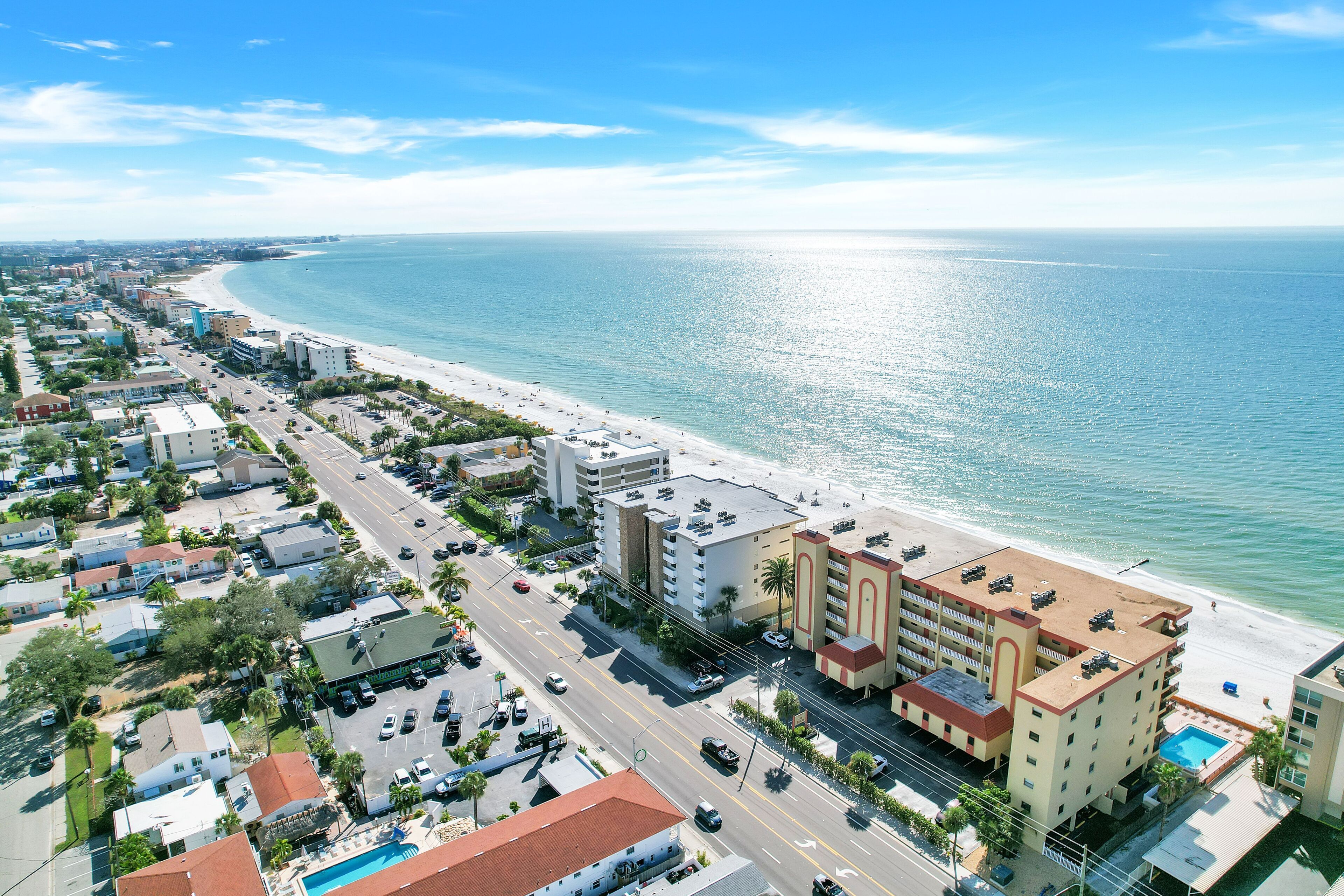 Un hôtel situé sur la côte, avec vue sur la plage, plusieurs étages et une piscine.
