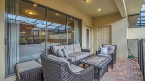 A balcony with wicker furniture, a glass door, and a view of the interior. - 5BD Windsor Westside Private Pool - WW 9025 (Kissimmee)