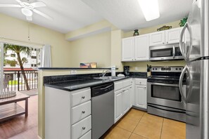 A modern kitchen with white cabinets, a stainless steel refrigerator, and a built-in microwave.