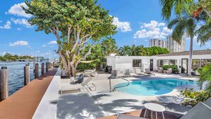 A poolside area with a wooden deck, lounge chairs, and a pool. - Beautiful Waterfront Condo on Canal with Pool & Walk to Beach! Boat Watch! 1b/1b (Pompano Beach)