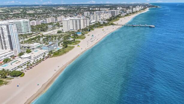 An aerial view of a coastal city with a long sandy beach, high-rise hotels, and a pier extending into the ocean. - Beautiful Waterfront Condo on Canal with Pool & Walk to Beach! Boat Watch! 1b/1b (Pompano Beach)