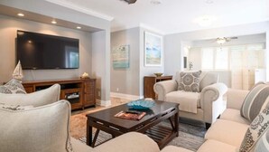 A living room with a flat-screen TV, a wooden entertainment unit, a coffee table, and two sofas. - Beautiful & Spacious Waterfront Condo, Walk to the BEACH, On Canal, 3 bed/2 bath (Pompano Beach)