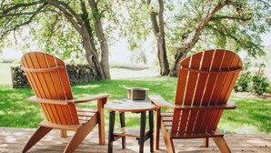 Two wooden Adirondack chairs on a wooden deck with a small round table. - Backyard Retreat (RONKS)