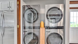 A modern kitchen with stainless steel appliances, including a refrigerator, a double oven, and a built-in washing machine. - Backyard Retreat (RONKS)