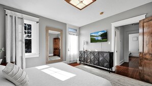 A bedroom with a bed, a TV, a wardrobe, and a mirror. - Backyard Retreat (RONKS)
