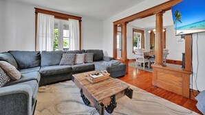 A living room with a sectional sofa, a coffee table, and a dining area with a wooden table and chairs. - Backyard Retreat (RONKS)